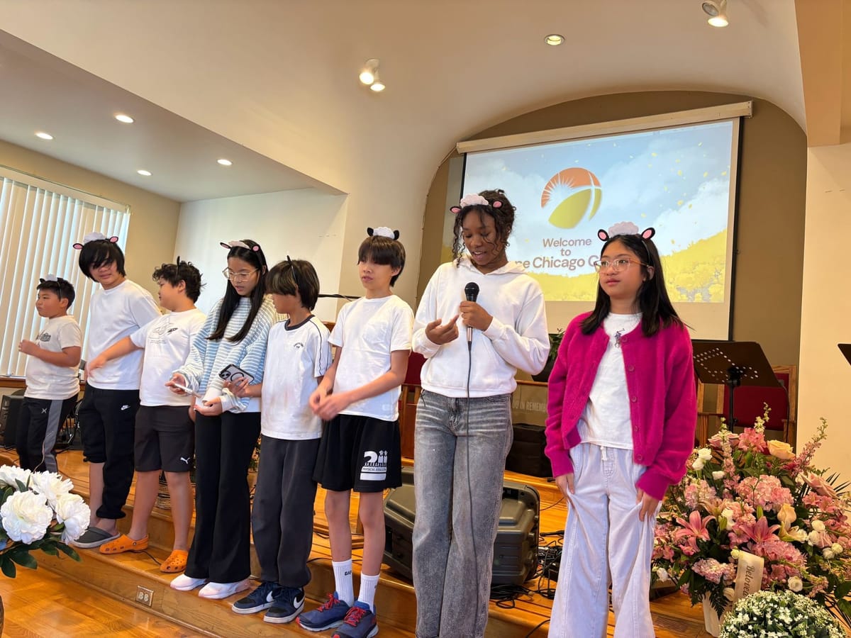 Eight children and teens in fluffy sheep-ear headbands standing in a line on the church stage, one speaking into a microphone, with a Welcome to Hope Chicago Church slide behind them