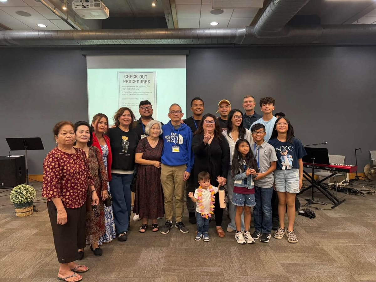 Adults and children standing together in a meeting room in front of a projector screen