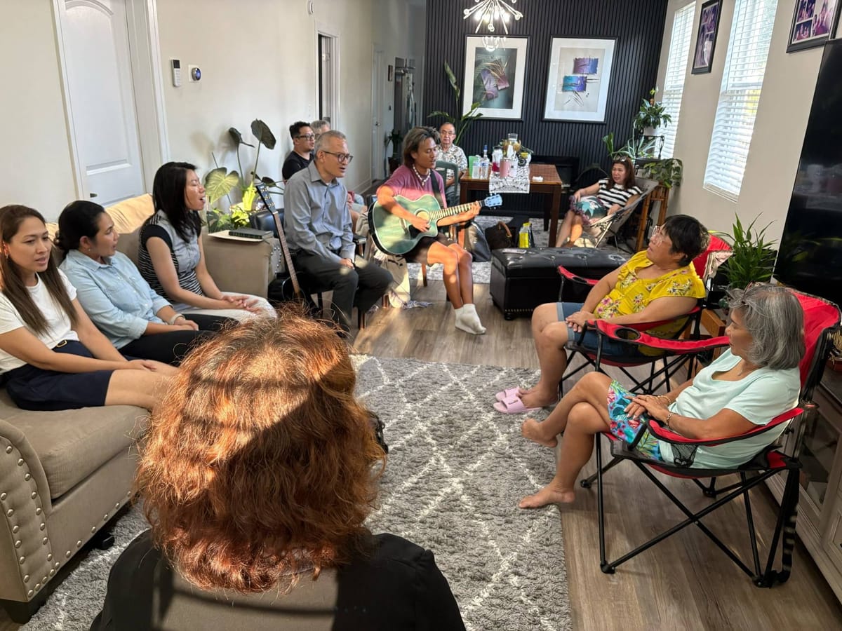 A Life Group singing together in a living room while a man plays an acoustic guitar